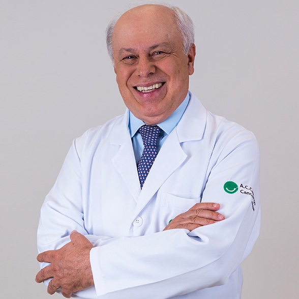 Doutor Ademar Lopes, careca, cabelo e pele branca, sorri de jaleco