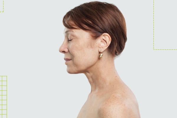 Senhora branca de uns 50 anos de perfil, olhos fechados, sem roupa do ombro para cima
