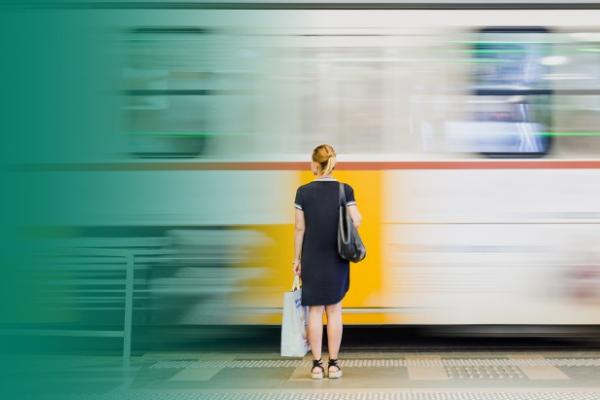Moça loira aguarda o trem de costas