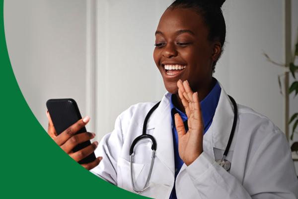 Mulher negra de jaleco sorri olhando para o celular