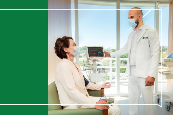 Médico atendendo uma paciente. Ao lado, uma arte gráfica retangular verde escuro.