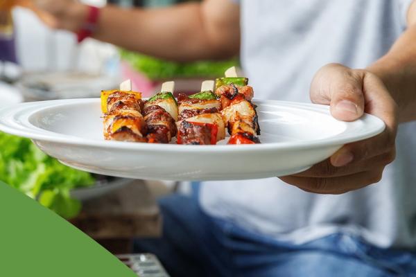 Homem branco segura um prato com churrasco