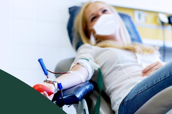 Mulher branca deitada em uma cadeira doando sangue.