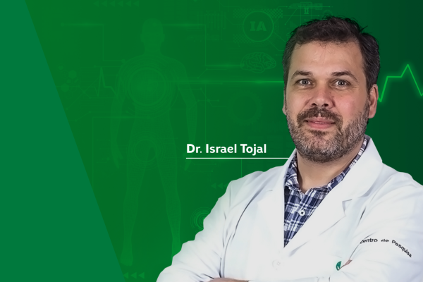 Montagem de uma foto do Dr. Israel Tojal. Ele usa um jaleco branco. 