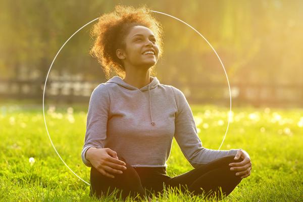 Jovem negra sorri meditando num parque