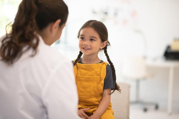 Mulher de avental branco conversando com criança