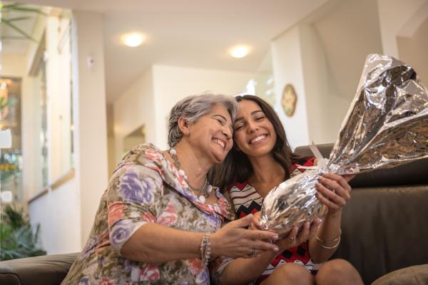 Mulher mais velha e uma mais nova entregando um ovo de páscoa