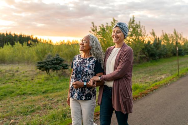 Duas mulheres andando em meio a natureza. Uma delas está com lenço na cabeça