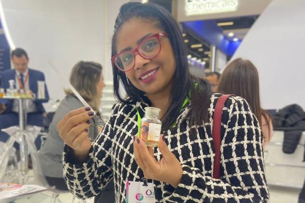 Uma mulher sentada em uma cadeira segurando um vidro com líquido aromático