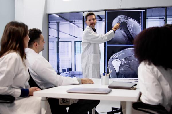 Vários médicos discutindo um caso clínico espelhado em exames na parede