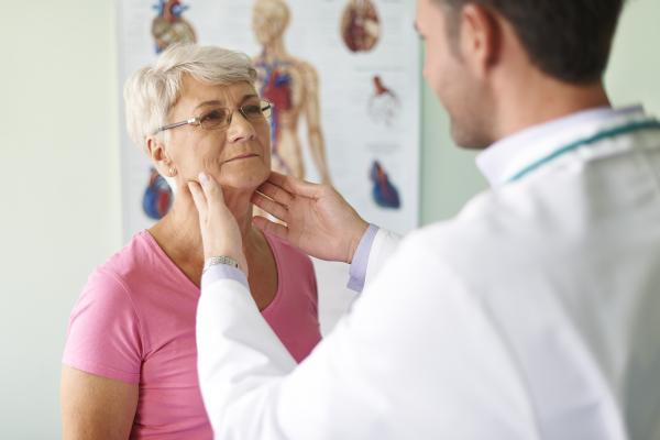 Uma senhora tendo o pescoço examinado por um médico