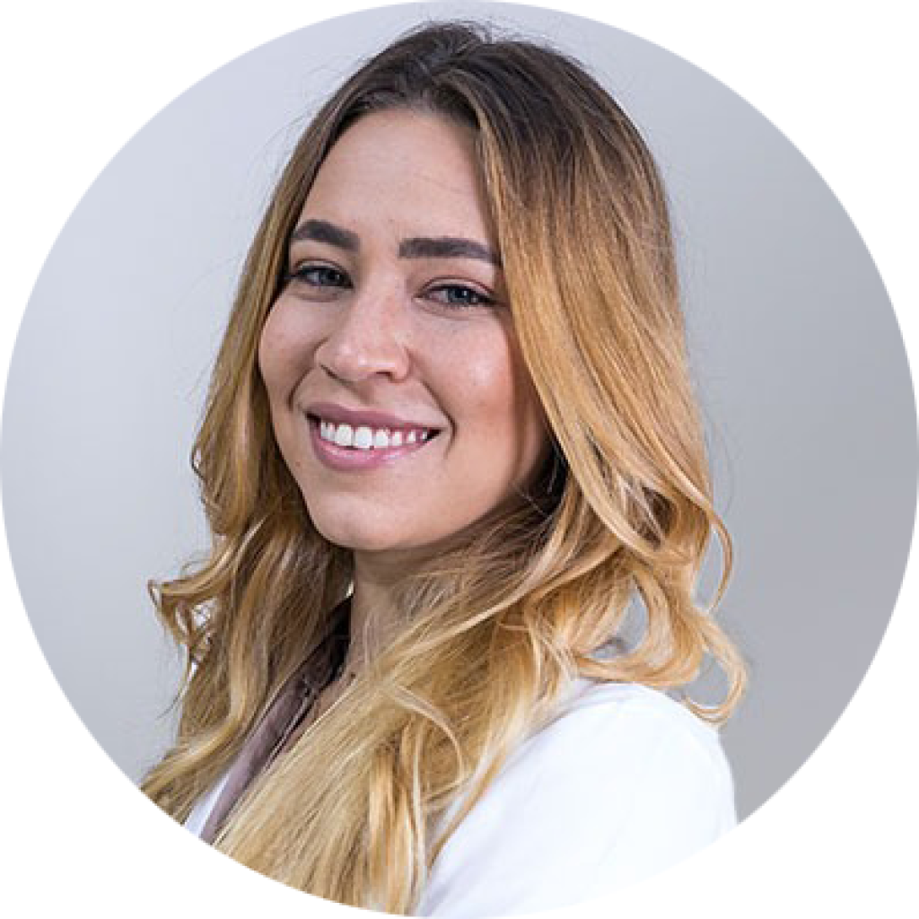 Carolina, 30 anos, loira, sorri de jaleco