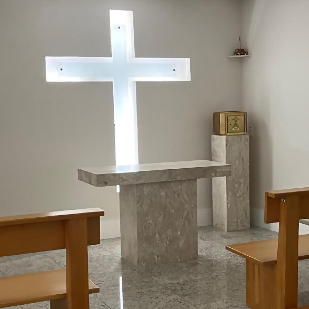 Uma foto de uma cruz de vidro iluminada e alguns bancos de madeira