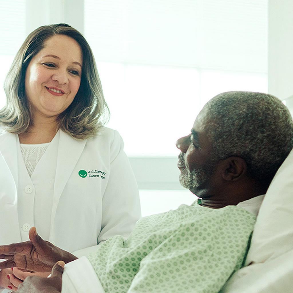 Um médico, uma médica e um paciente acamado
