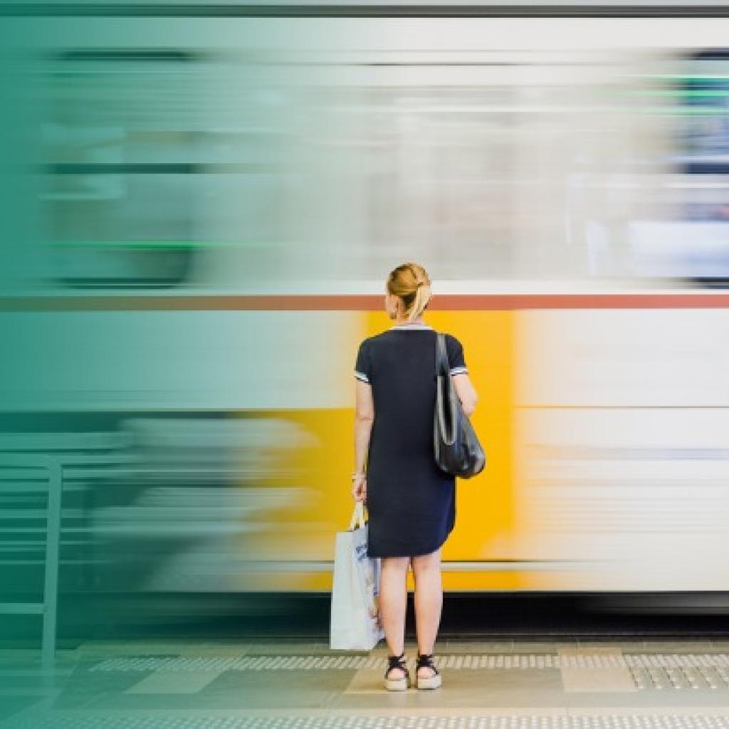 Moça loira aguarda o trem de costas