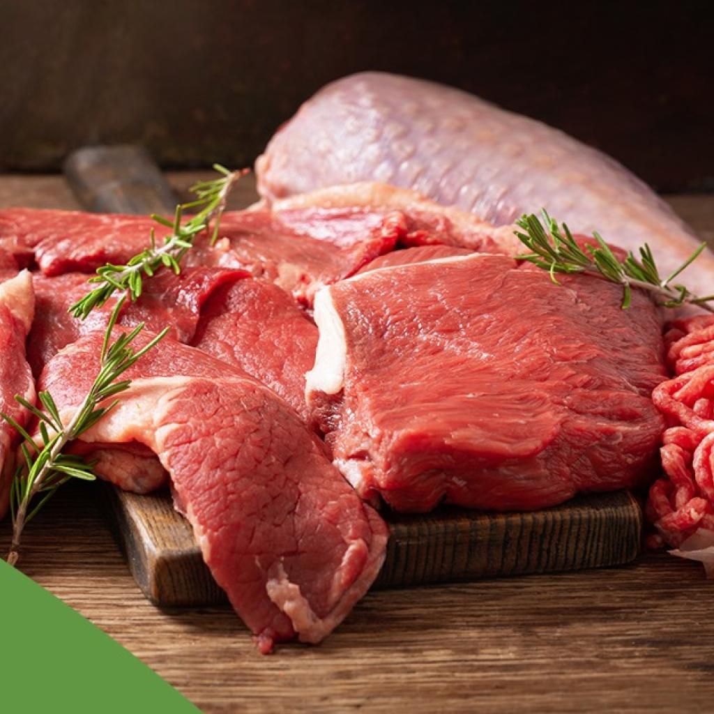 Carne vermelha crua e temperada sobre uma mesa de madeira