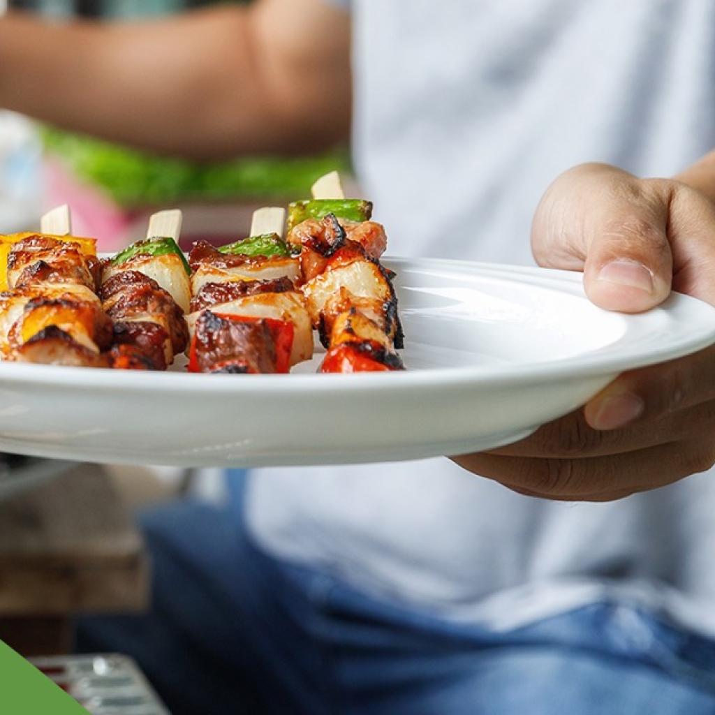 Homem branco segura um prato com churrasco