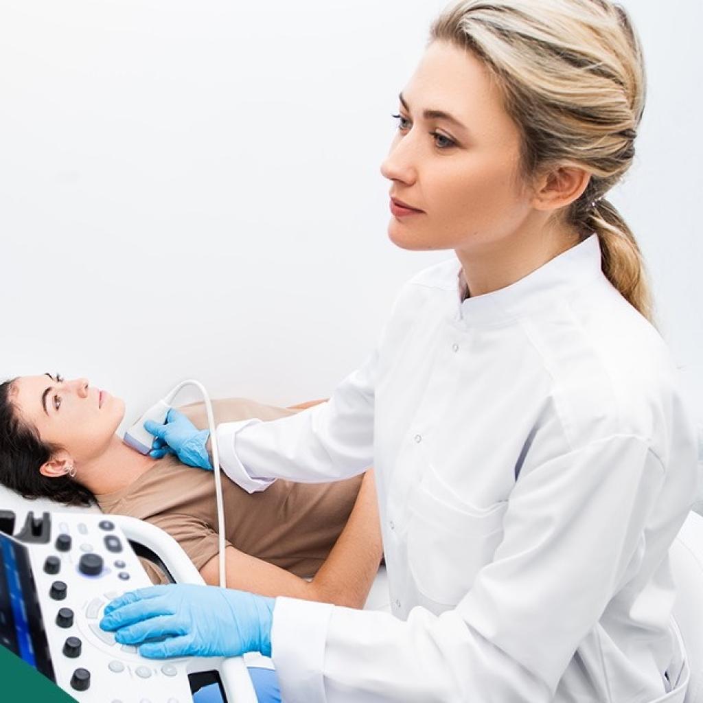 Médica fazendo ultrassom de tireoide em uma paciente mulher. Ambas são brancas e jovens.