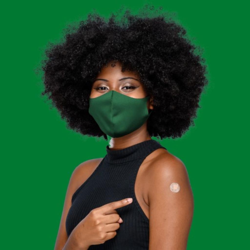 Mulher negra com máscara verde e braço vacinado, cabelo black power
