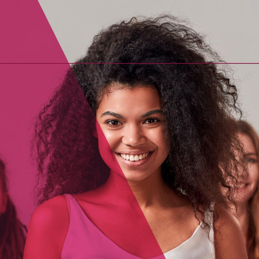 Cinco mulheres olhando para a foto e sorrindo. A mulher principal é uma moça preta, com cabelo cacheado, sorrindo para a foto.