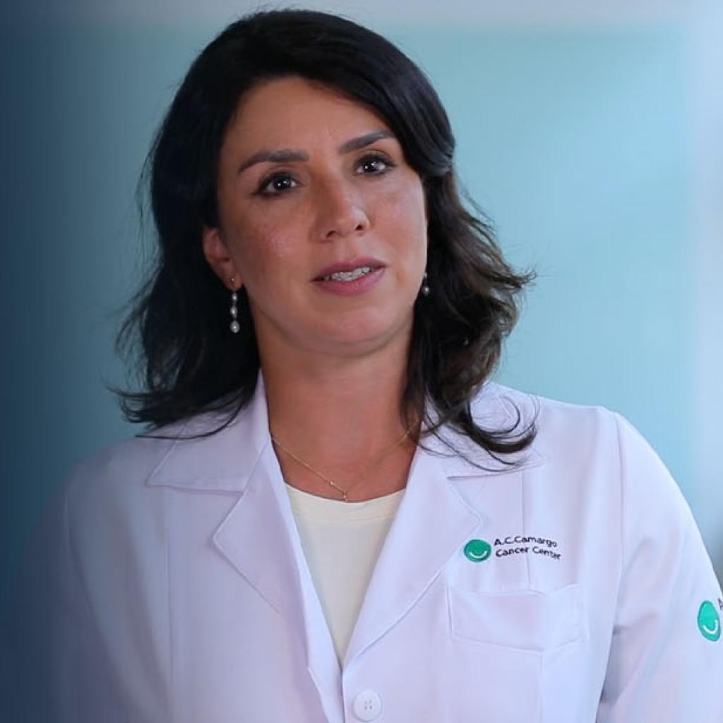 Doutora Rachel Riechelmann, branca, 40 anos, cabelos negros e longos, sorri de jaleco