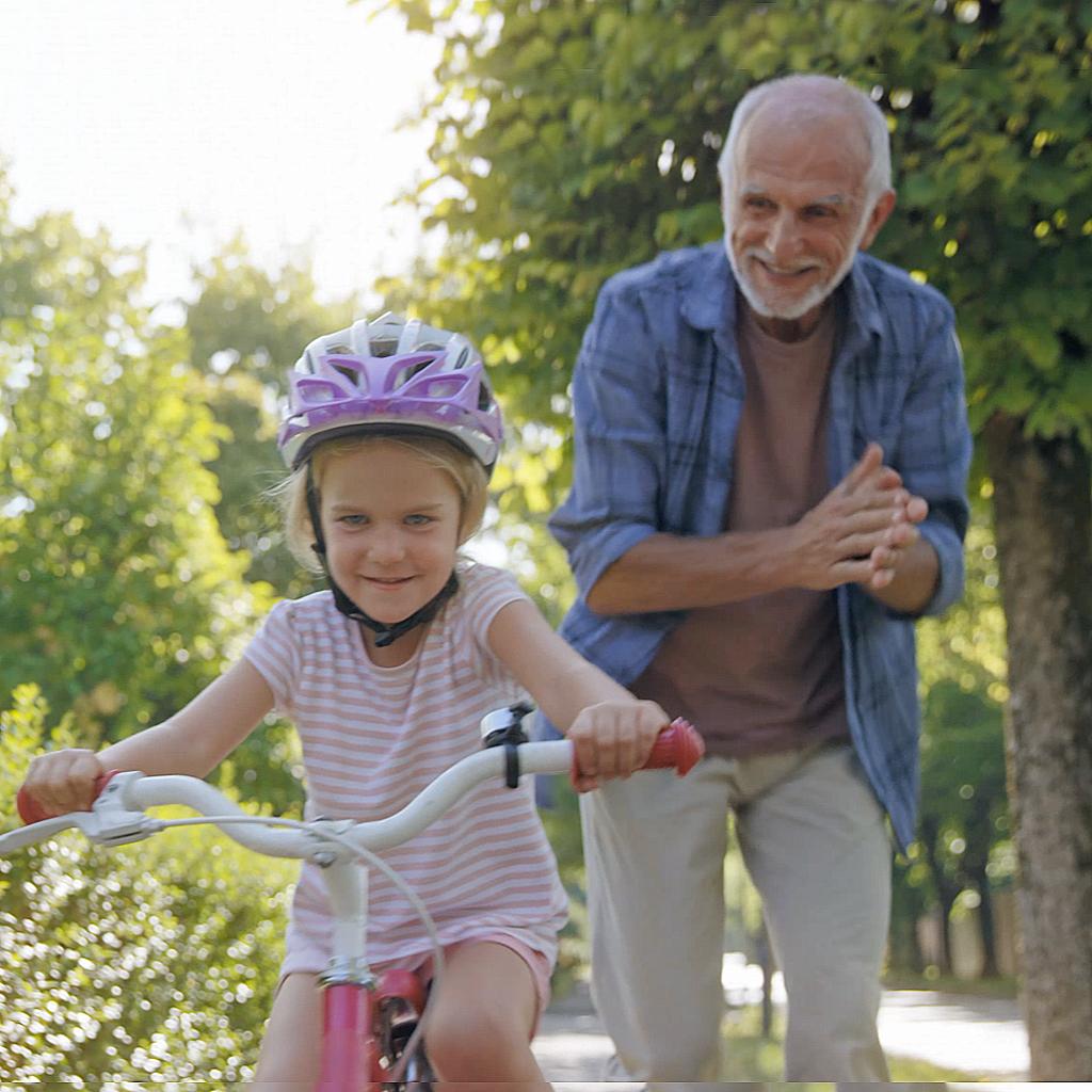 Imagem de um homem idoso aplaudindo e de uma menina aprendendo a andar de bicicleta