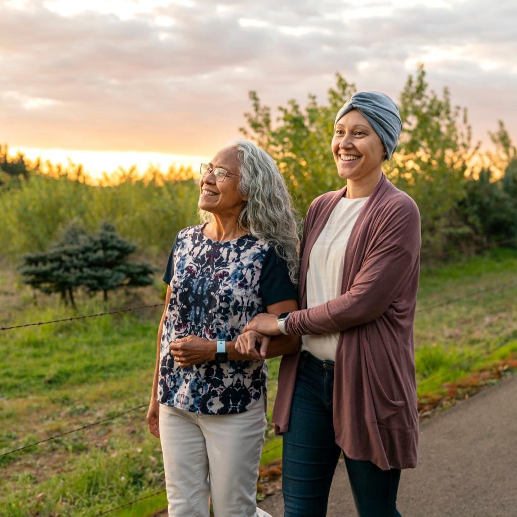 Duas mulheres andando em meio a natureza. Uma delas está com lenço na cabeça