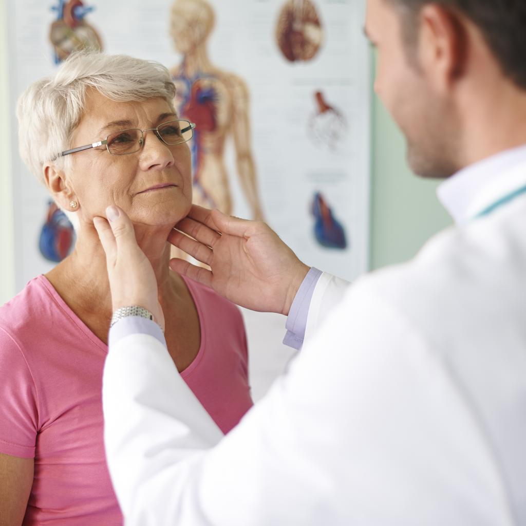 Uma senhora tendo o pescoço examinado por um médico