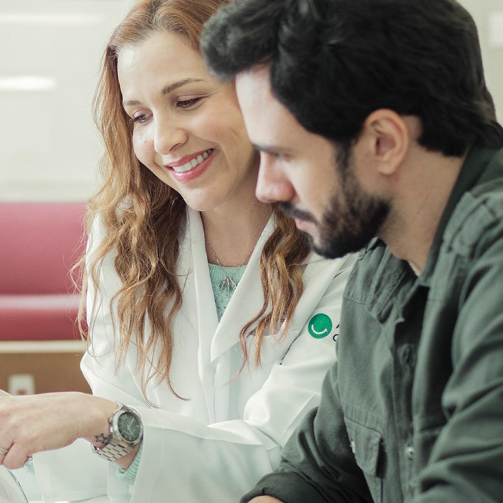 Uma médica explicando um caso para um homem com uma prancheta