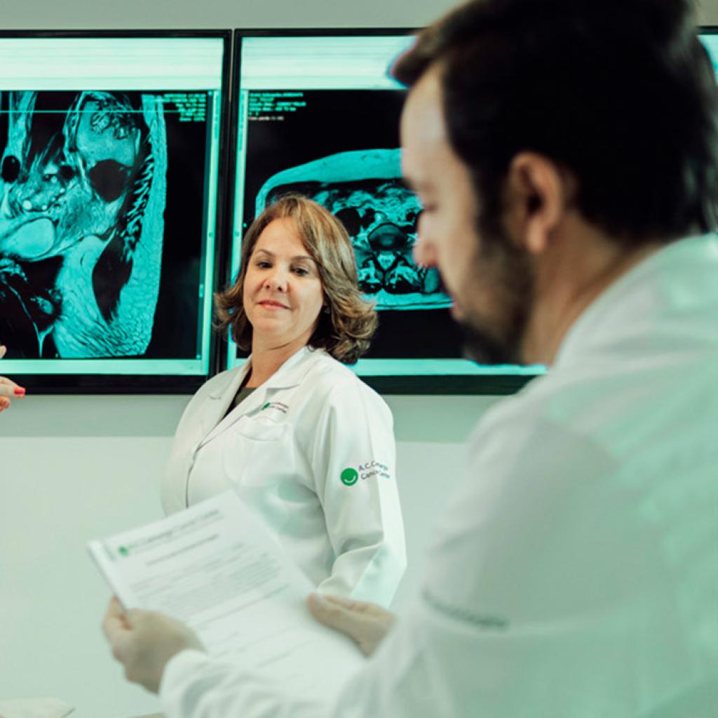 Quatro médicos avaliando um caso em televisores