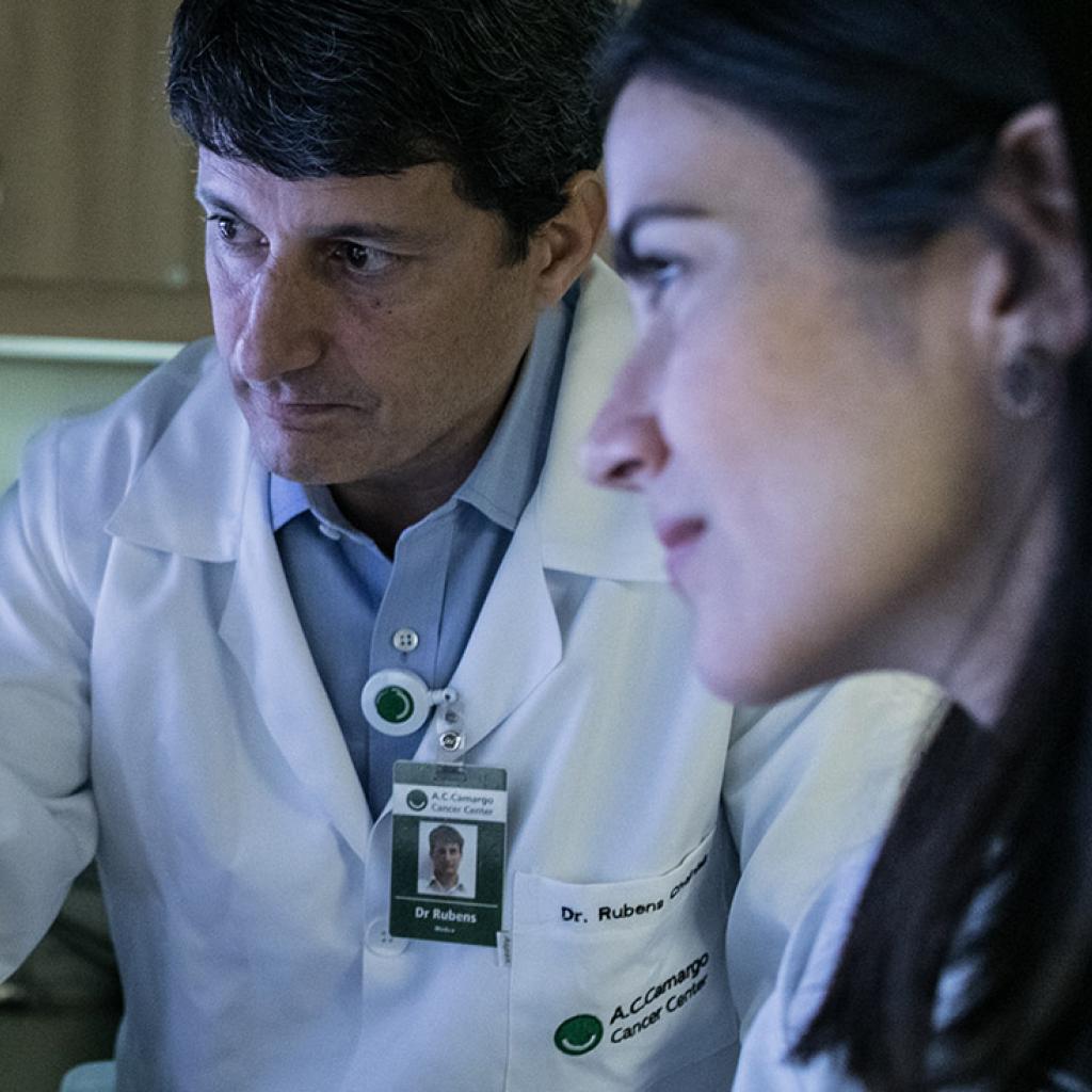 Um médico e uma médica analisando um exame de imagem em um computador