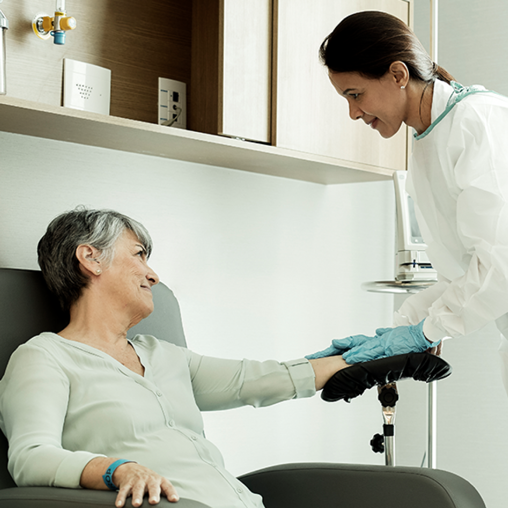 Uma enfermeira aplicando quimioterapia em uma paciente idosa