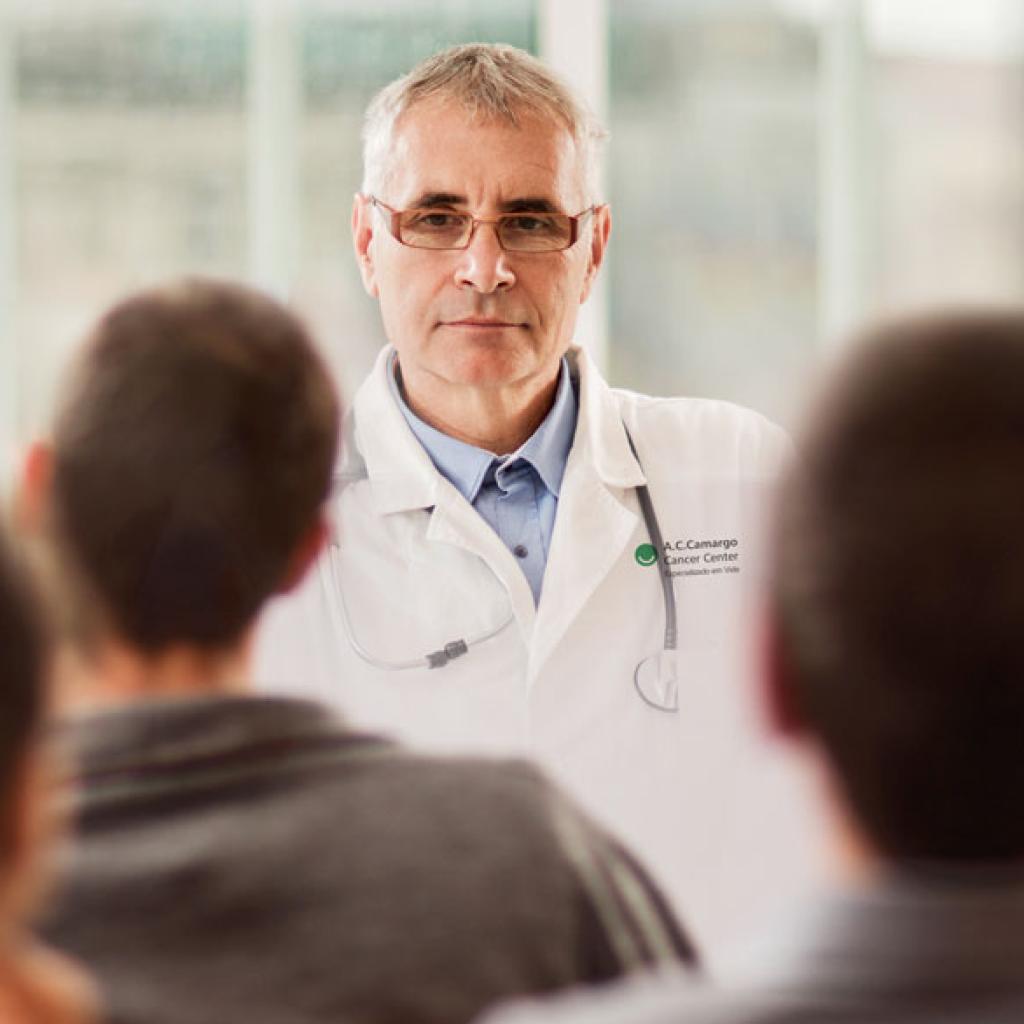 Um grupo de pessoas assistindo a apresentação de um médico
